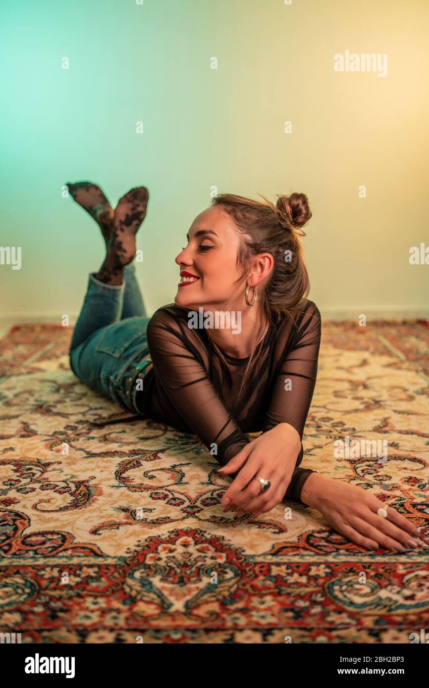Portrait of smiling young woman lying on carpet Stock Photo