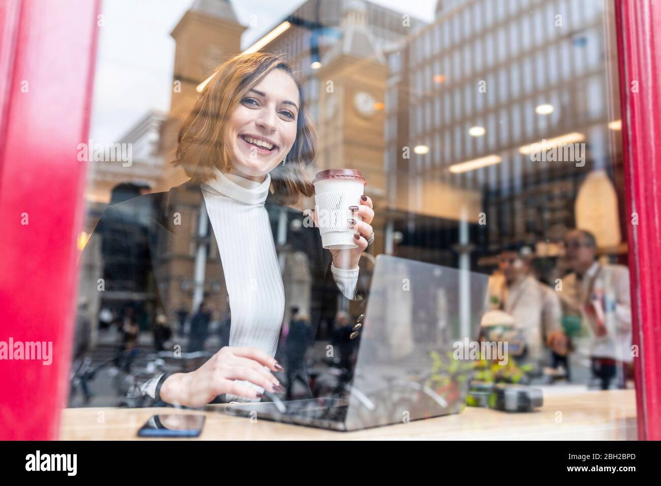 Portrait of happy businesswoman using laptop at a cafe in the city Stock Photo