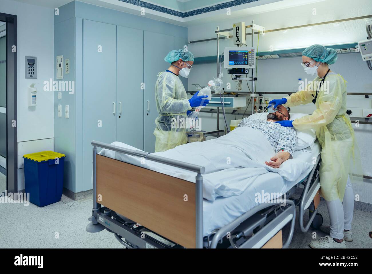 Doctors caring for patient in emergency care unit of a hospital changing breathing from oxygen mask to bag valve mask Stock Photo