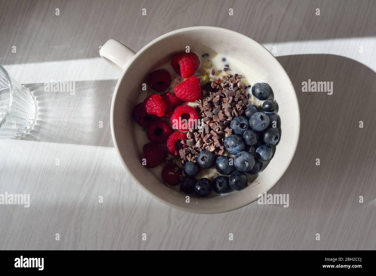 A bowl of porridge with fresh blueberries,raspberries and cocoa nibs Stock Photo