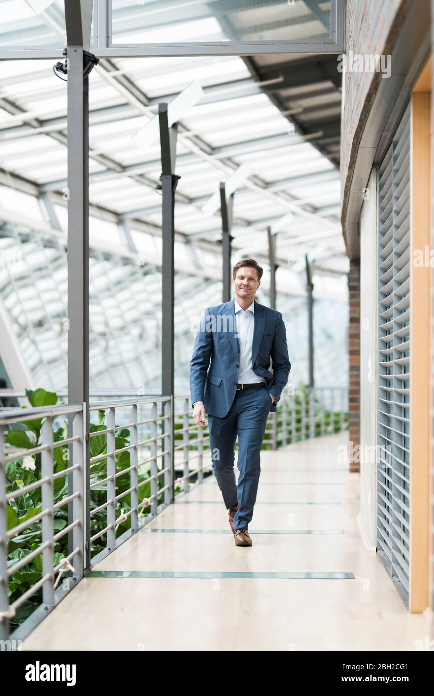 Confident businessman walking on gallery of green atrium Stock Photo