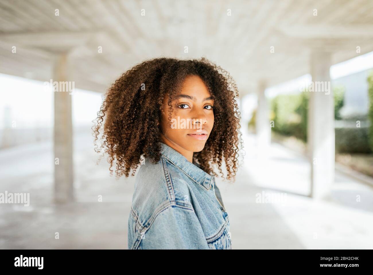 Portrait of young smiling woman pulling her hair up in a parking Stock ...