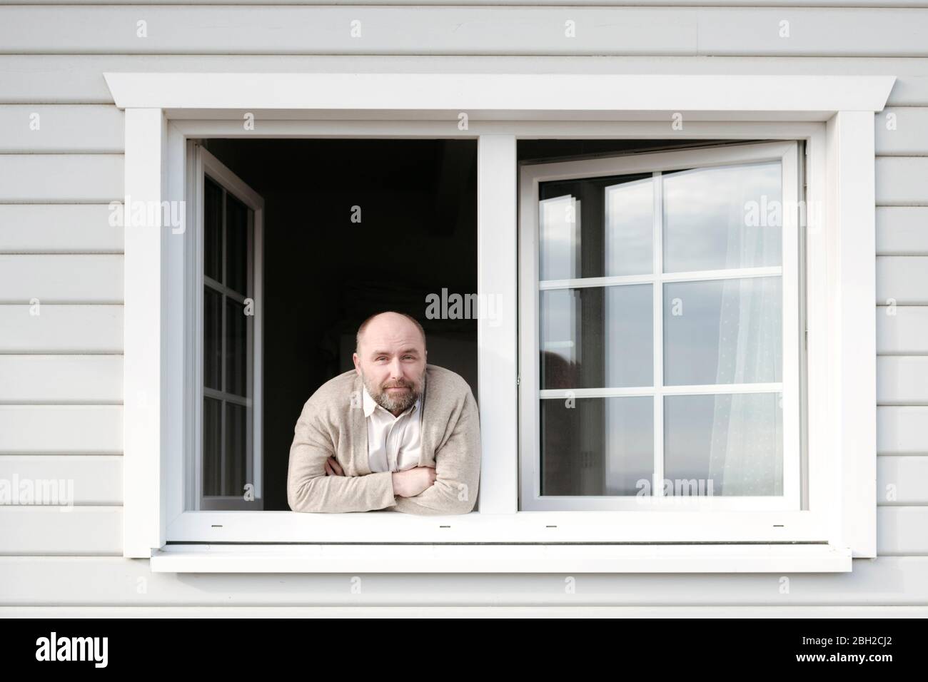 Portrait of mature man leaning out of window of his house Stock Photo