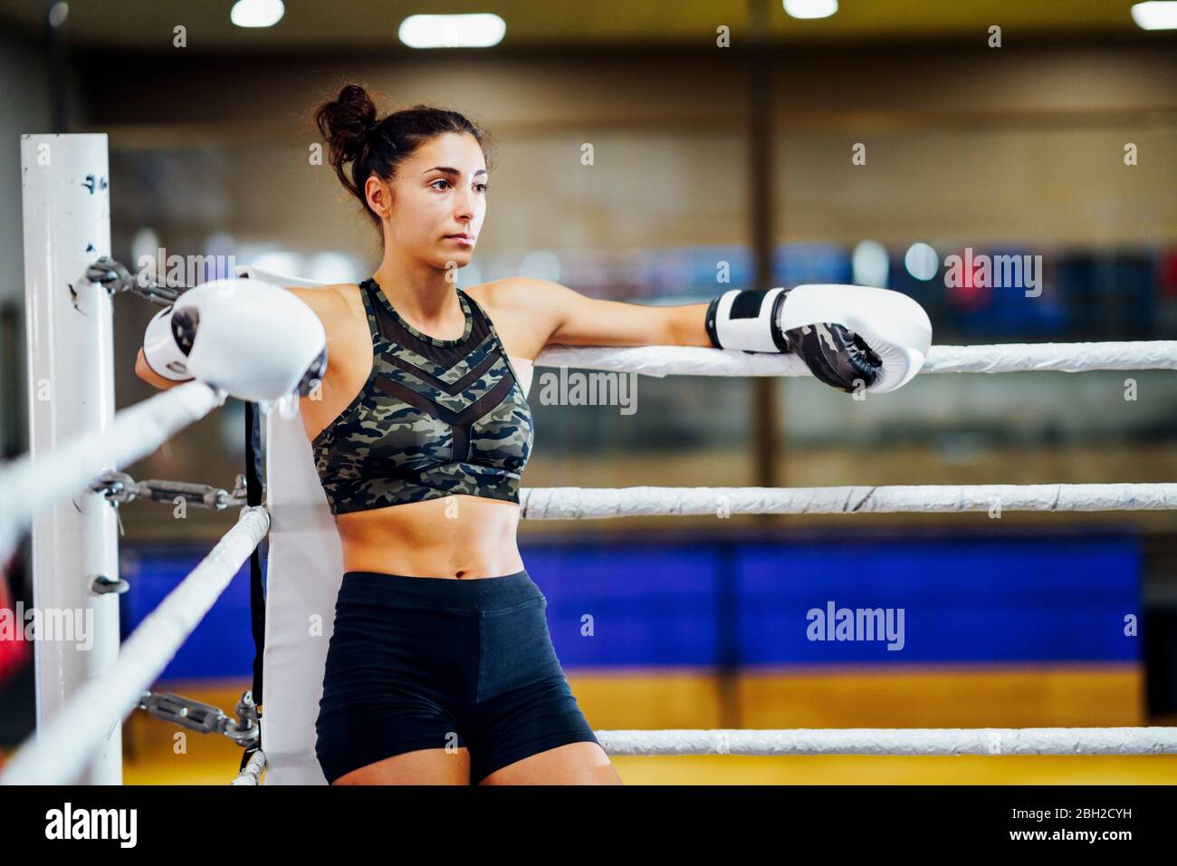 Athletic female boxer in boxing ring leaning on rope in the corner Stock Photo