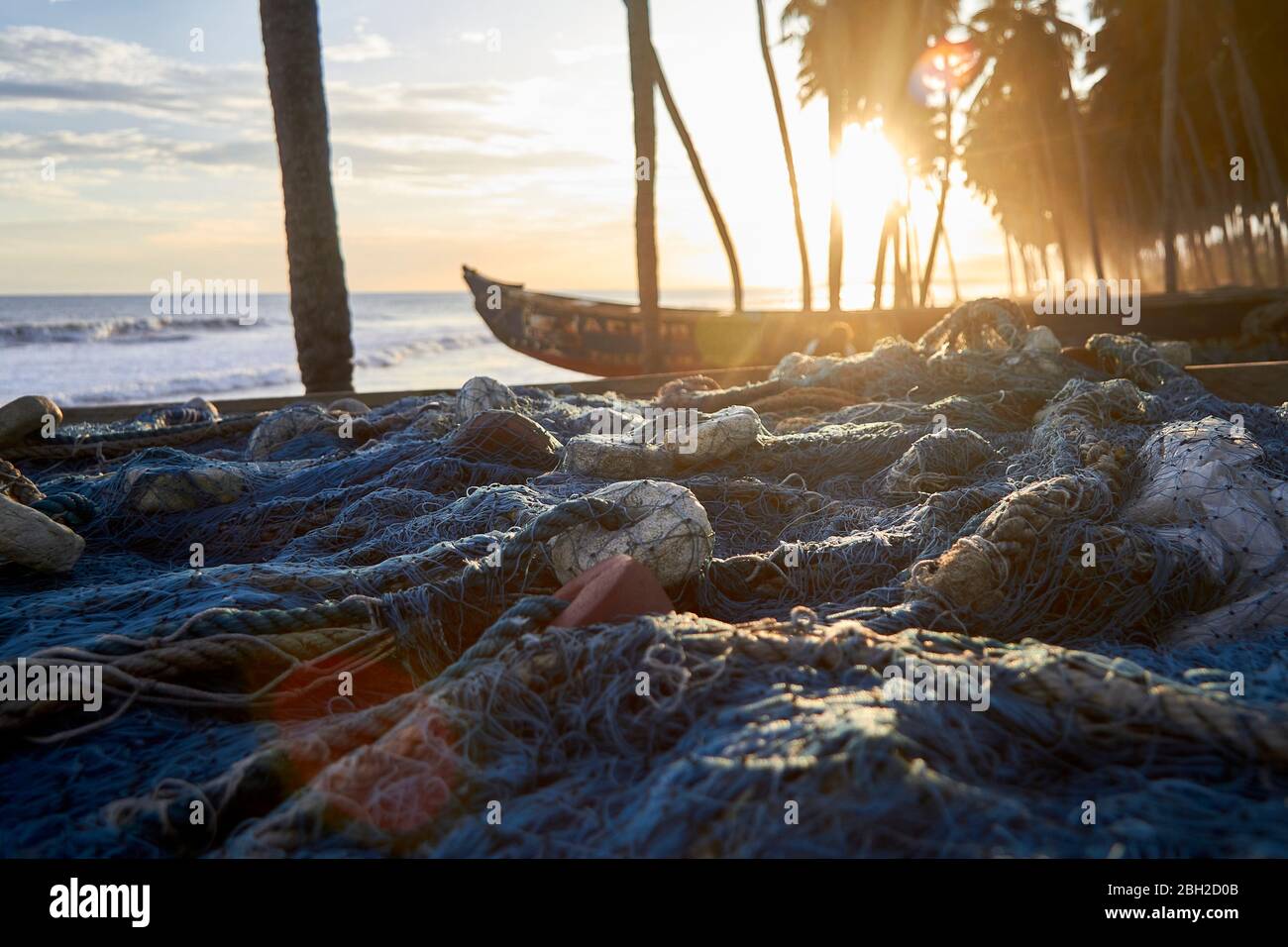 Ghana, Keta, Fishing nets lying in front of boats left on coastal beach at sunset Stock Photo