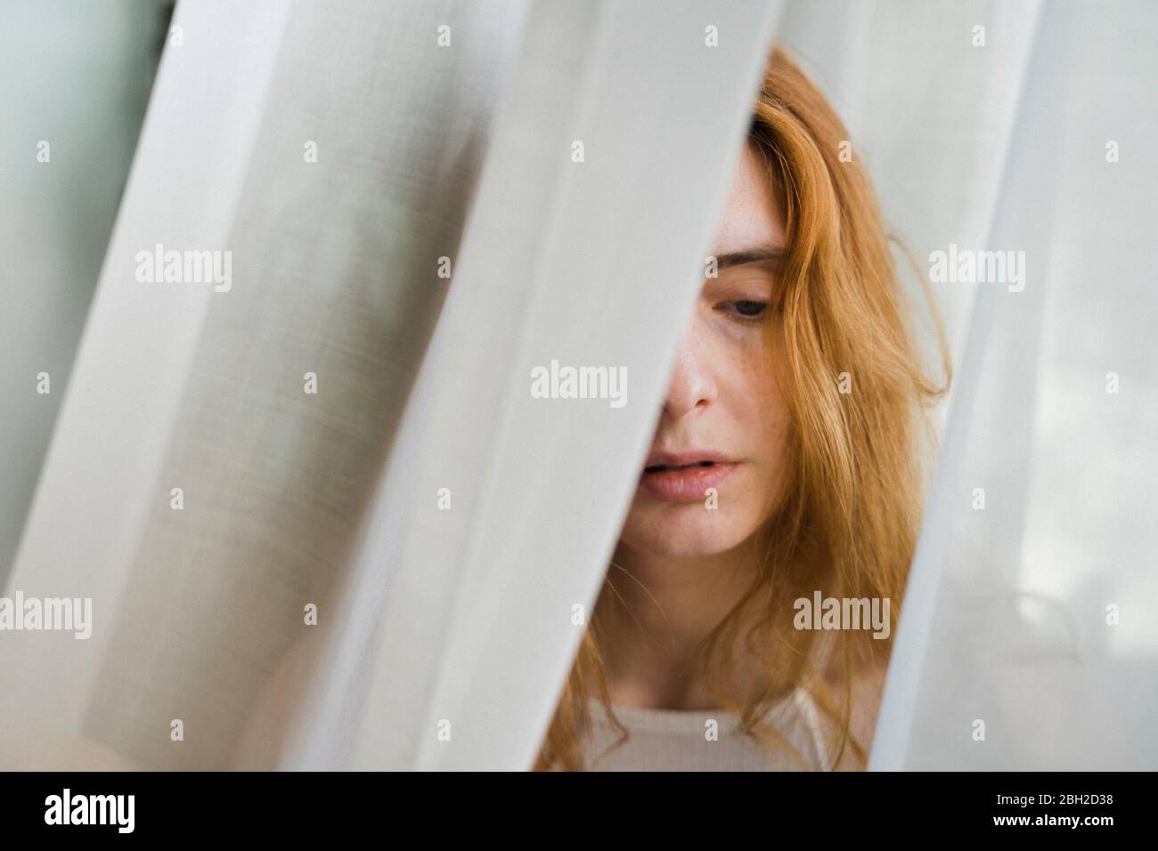 Portrait of sad young woman in a curtain Stock Photo