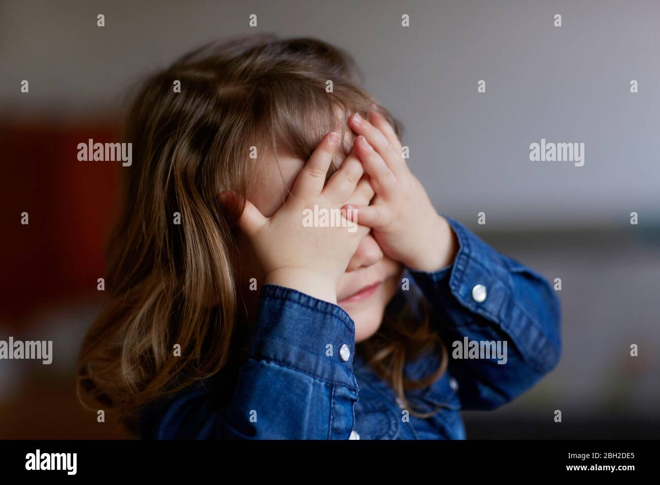 Portrait of toddler girl covering eyes with her hands Stock Photo