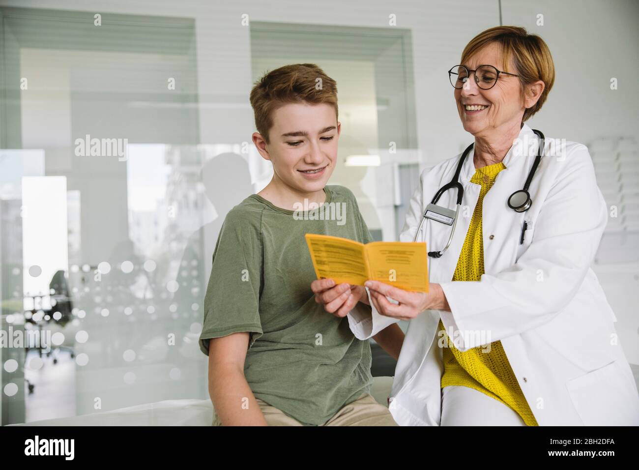 Doctor explaining vaccination to teenage boy in medical practice Stock Photo