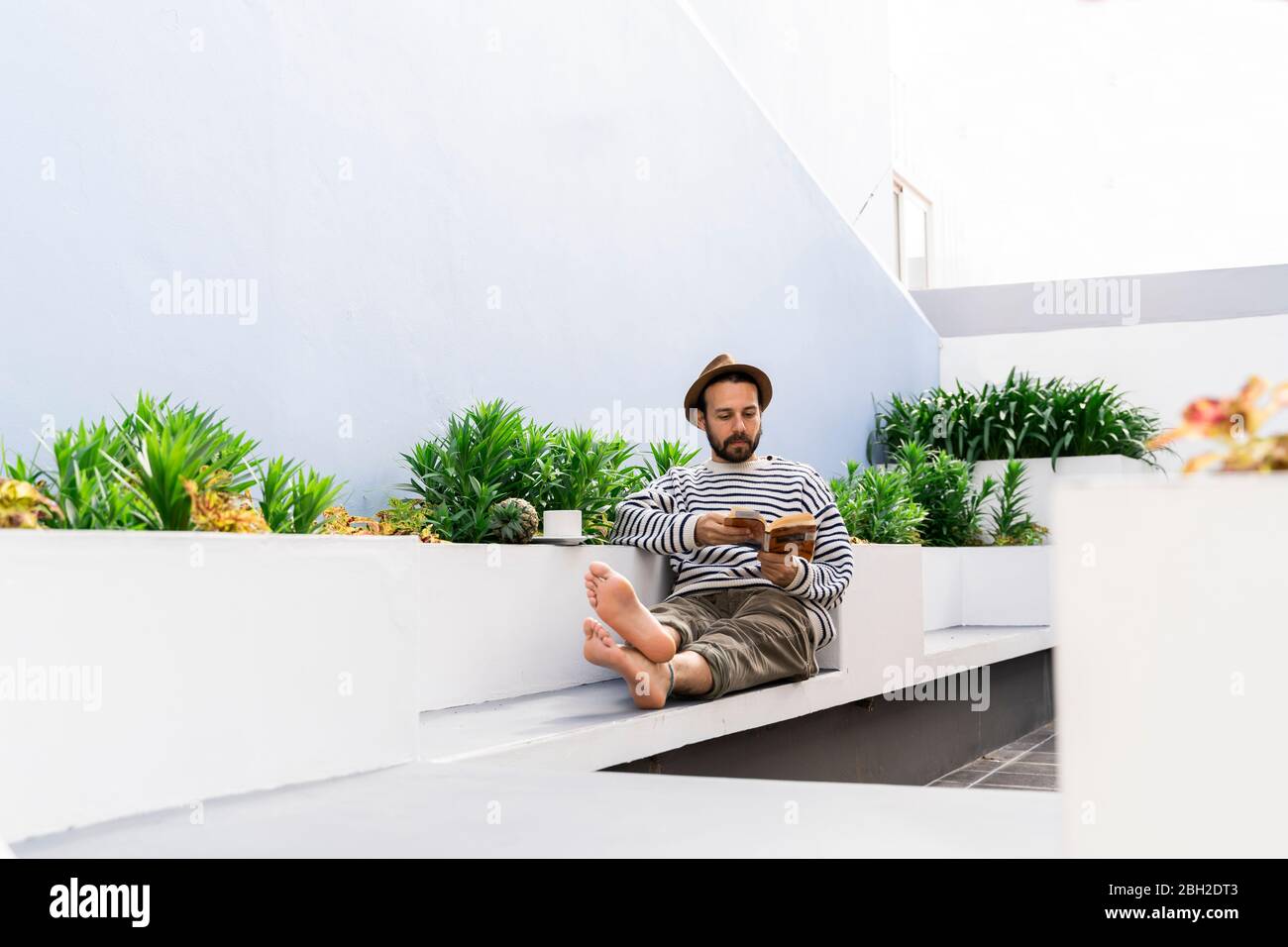 Man sitting on balcony reading a book Stock Photo