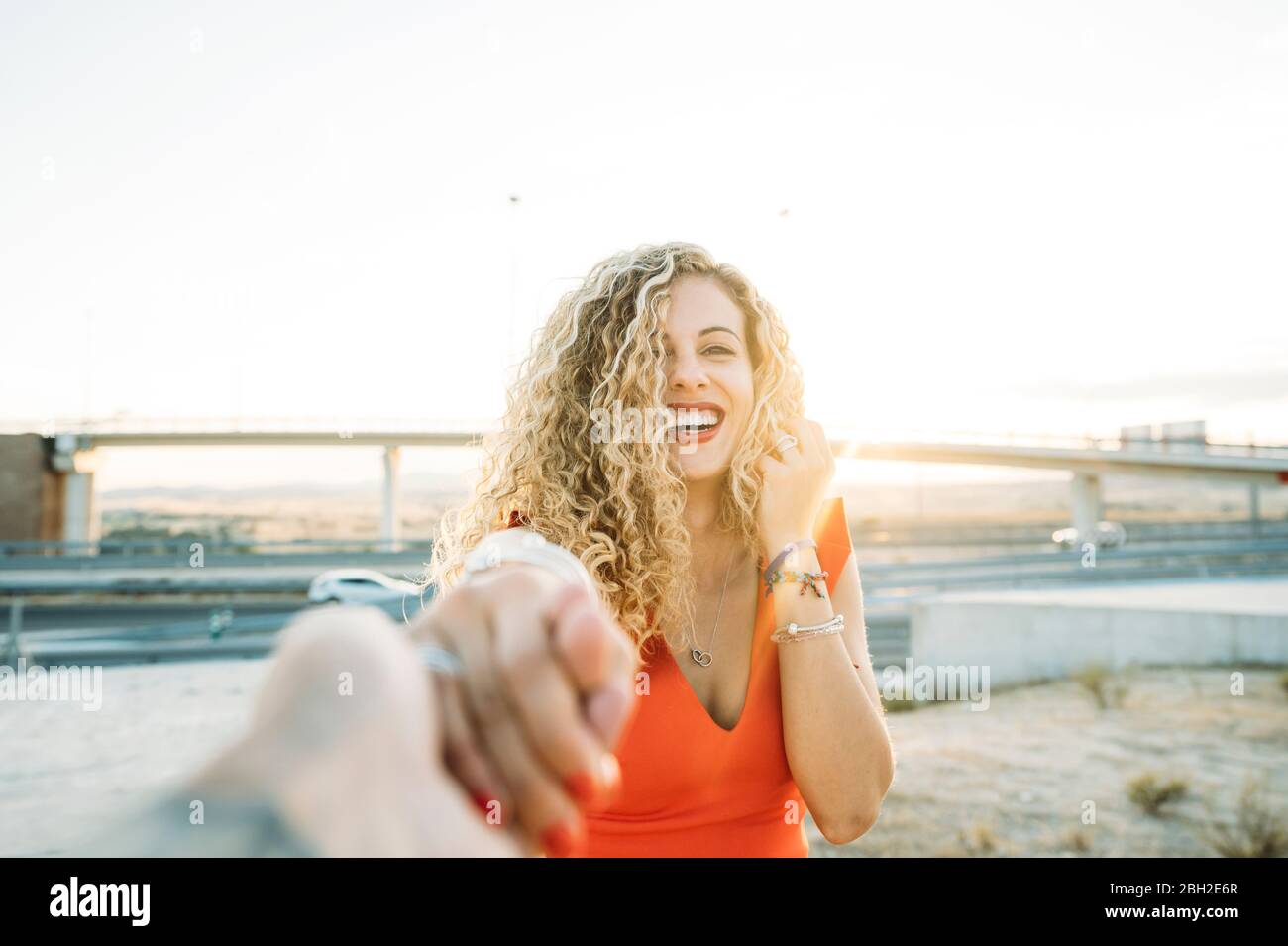 Portrait of happy young woman holding hands at evening twilight Stock Photo