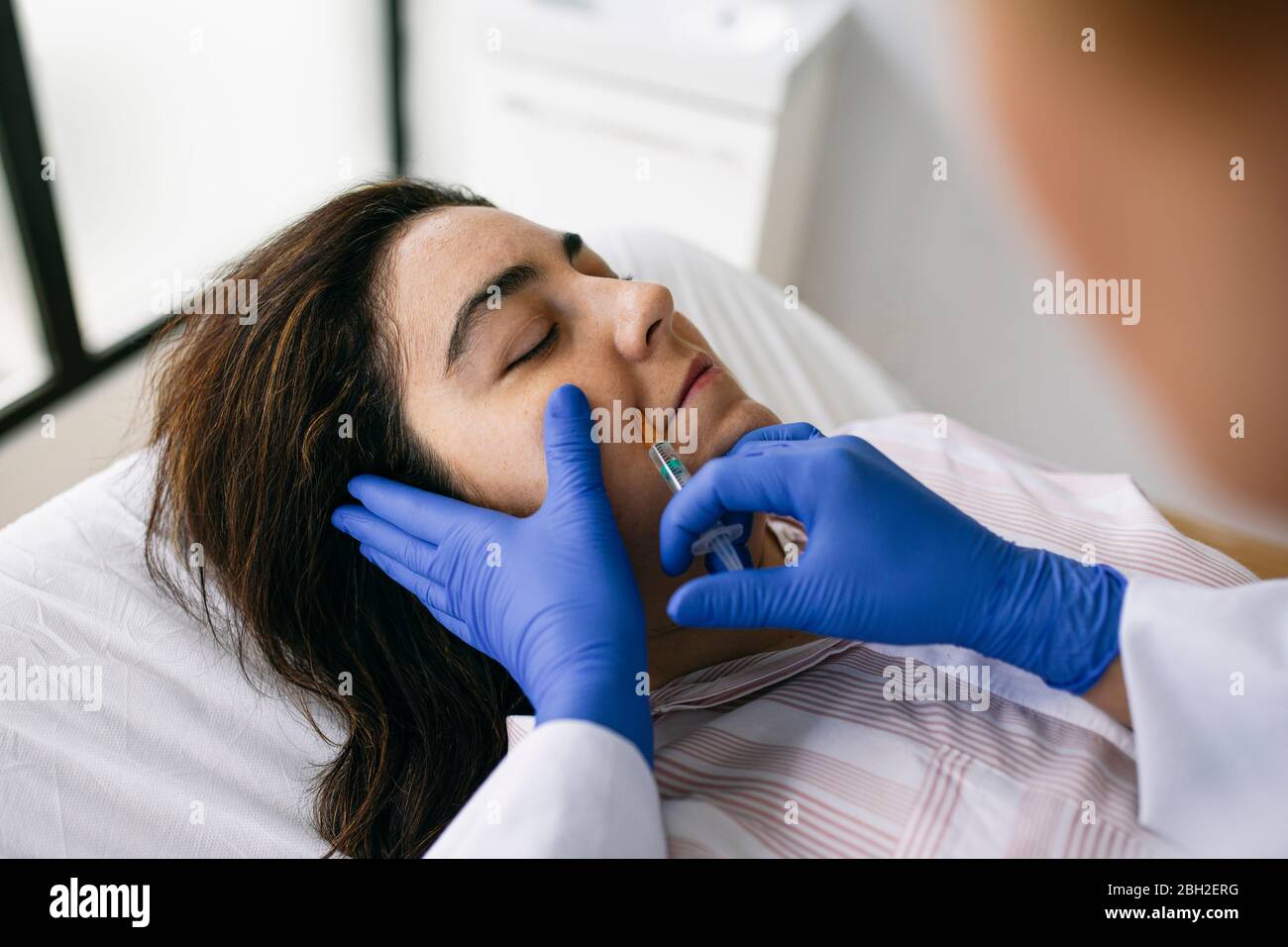 Woman receiving hyaluronic acid injection in medical practice Stock Photo