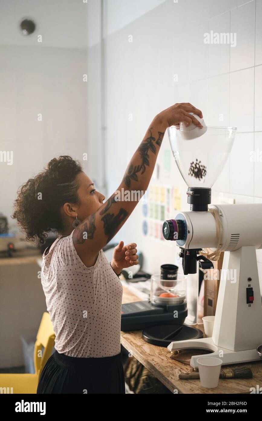 Woman working in a coffee roastery pouring coffee beans into a coffee
