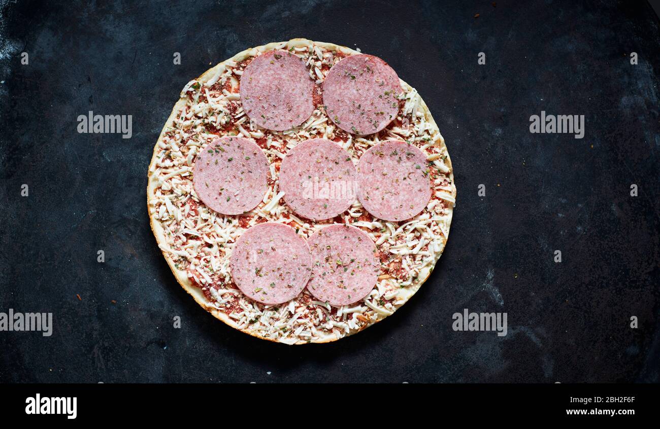 Frozen pizza with salami and grated cheese Stock Photo