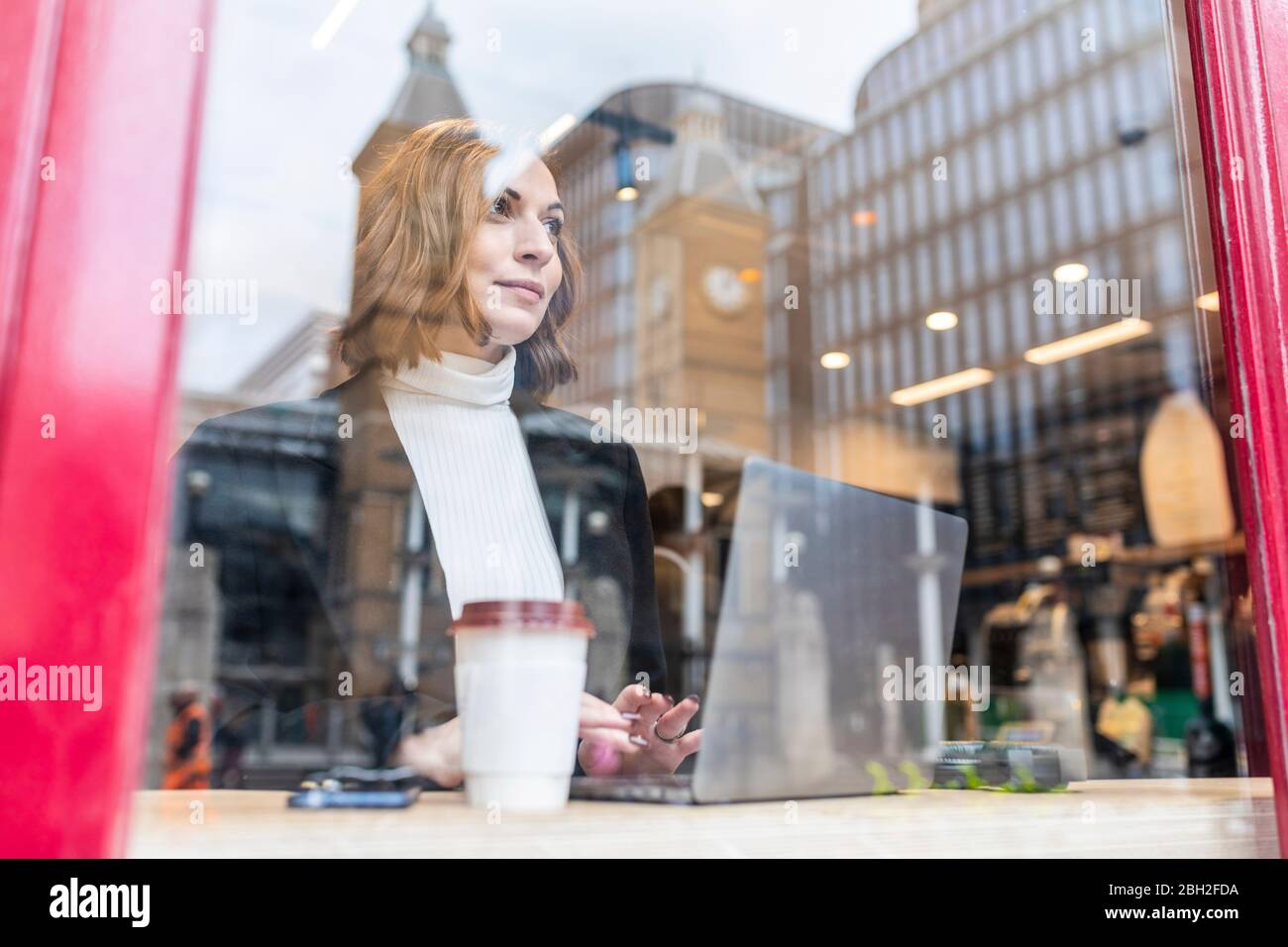 Businesswoman using laptop at a cafe in the city Stock Photo