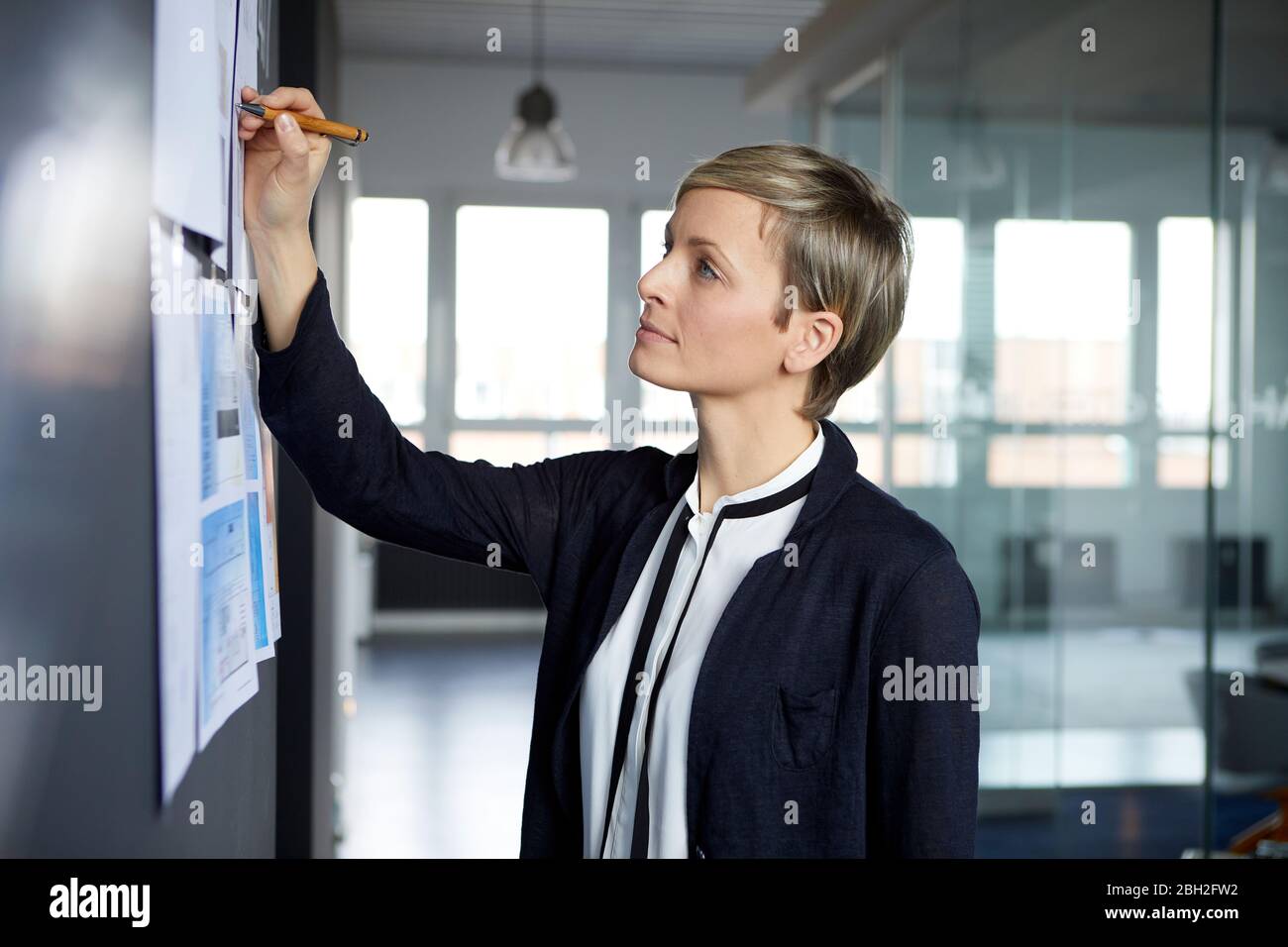 Businesswoman writing on paper at the wall in office Stock Photo