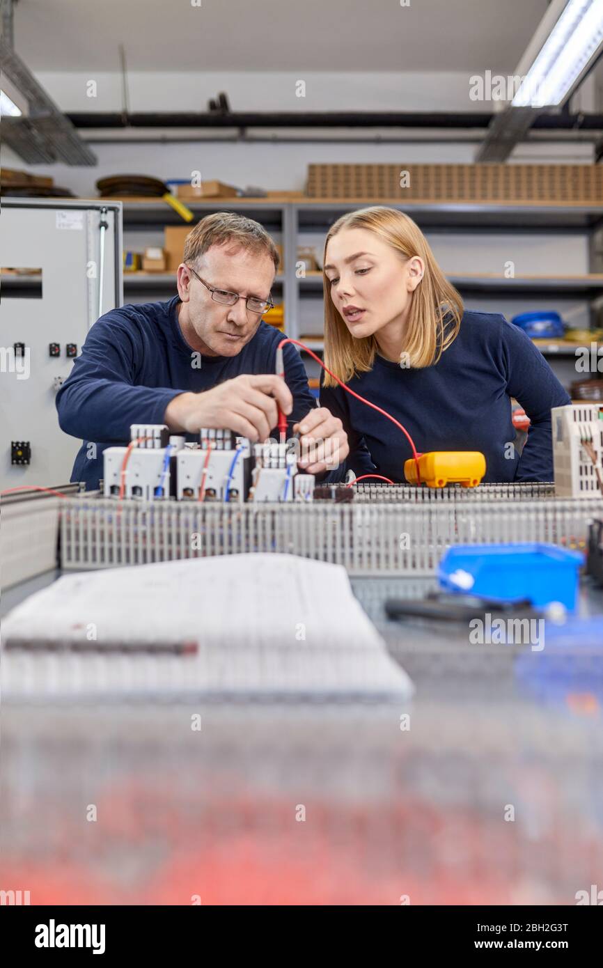 Two electricians working on circuitry in workshop Stock Photo
