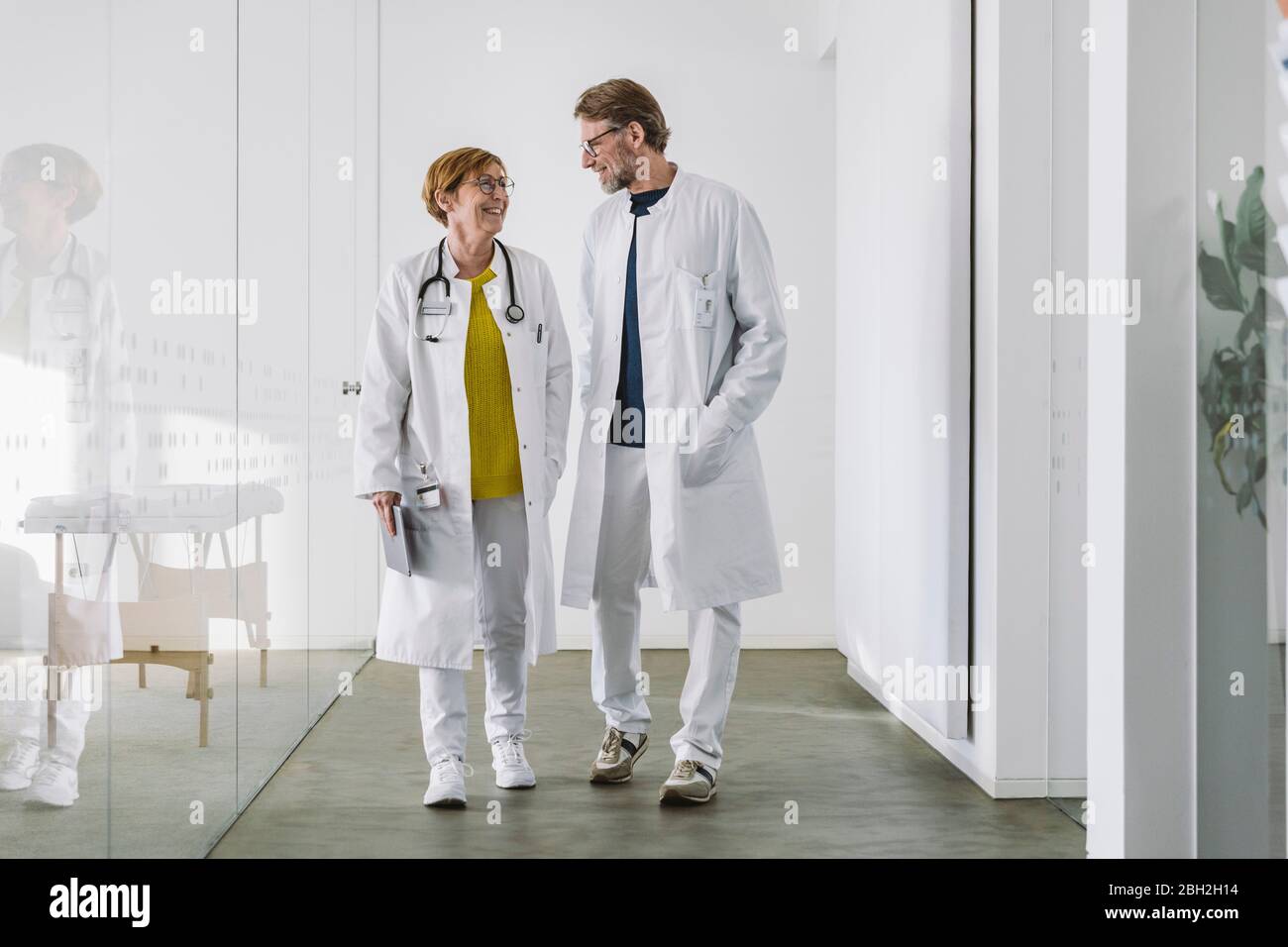 Two doctors discussing waking along hallway Stock Photo