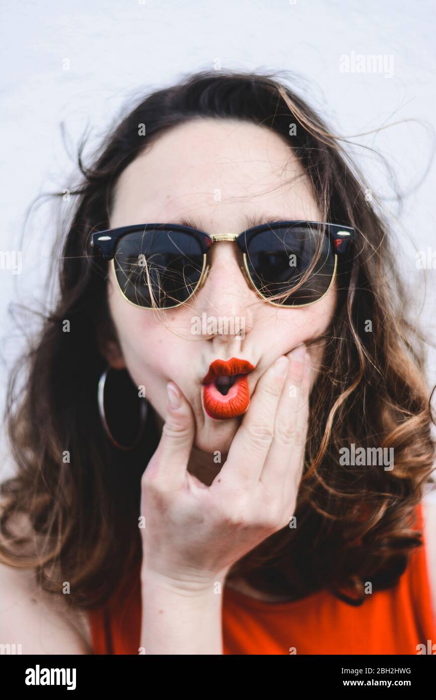 Portrait of young woman with red lips wearing sunglasses pouting mouth Stock Photo