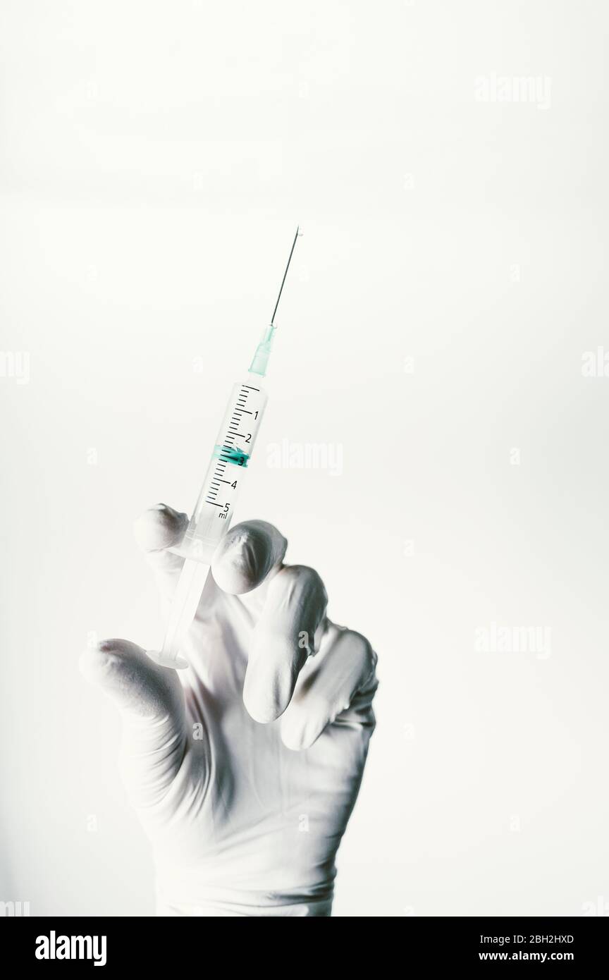 Hand with protective glove, holding syring with vaccine Stock Photo