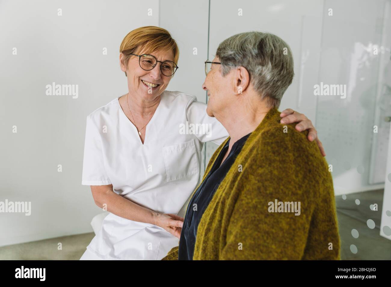 Doctor’s assistant encouraging senior patient in medical practice Stock Photo