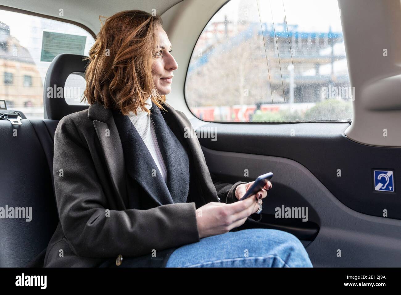 Businesswoman in the rear of a taxi looking out of the window, London, UK Stock Photo