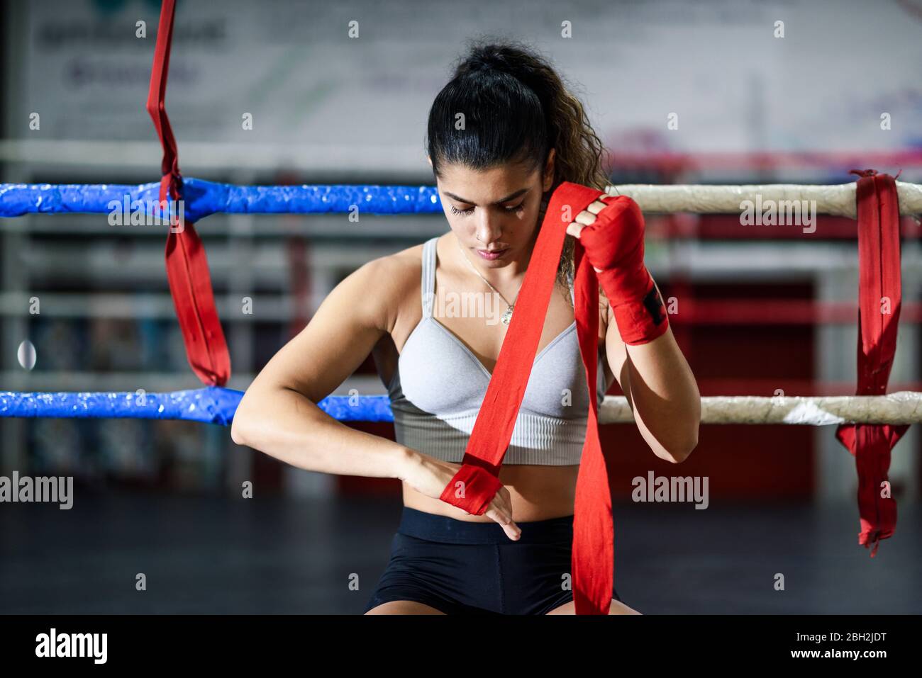 Young woman tying bandage around her hand in boxing club Stock Photo