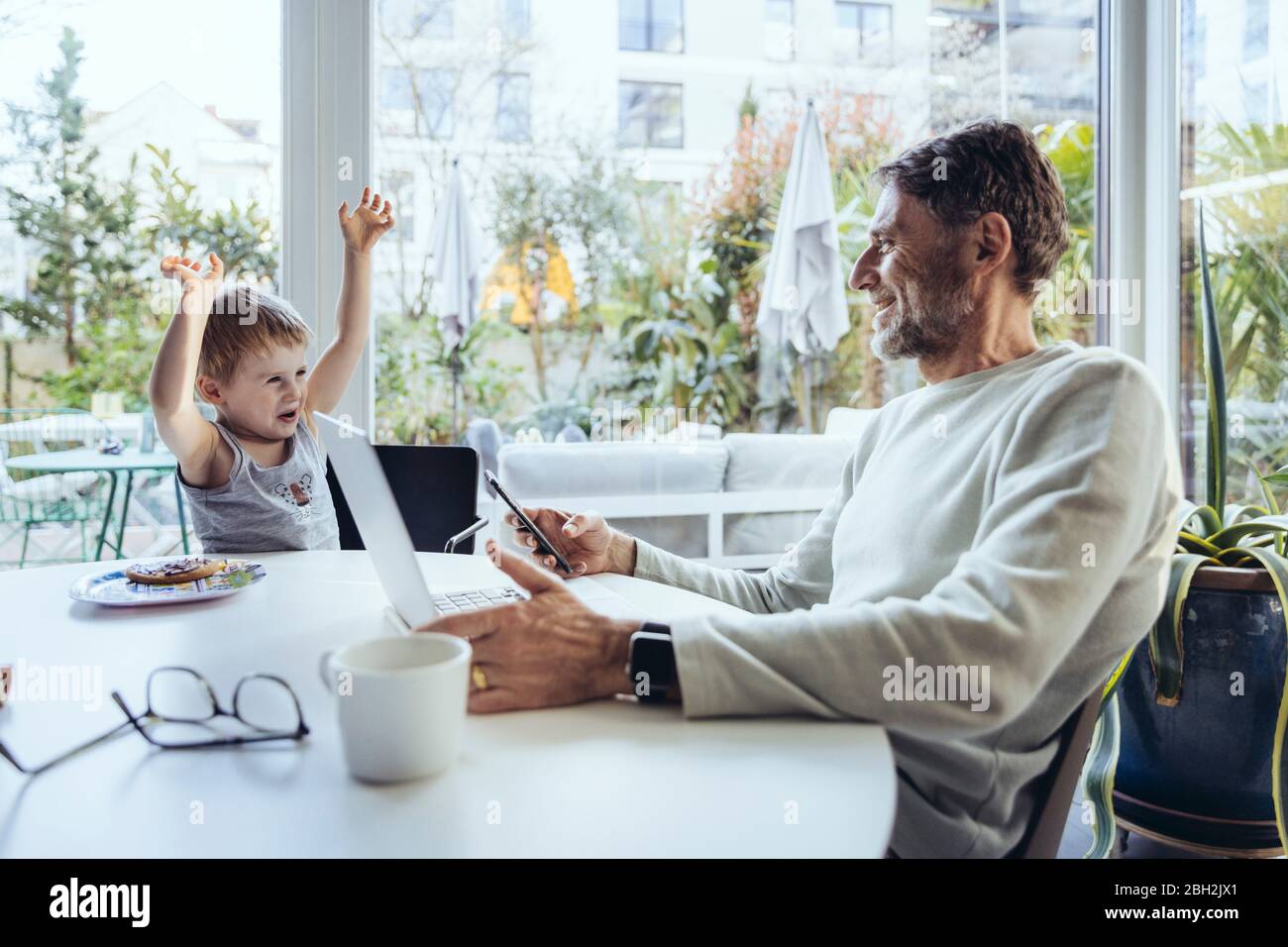 Little boy trying to get attention, while father is working from home Stock Photo