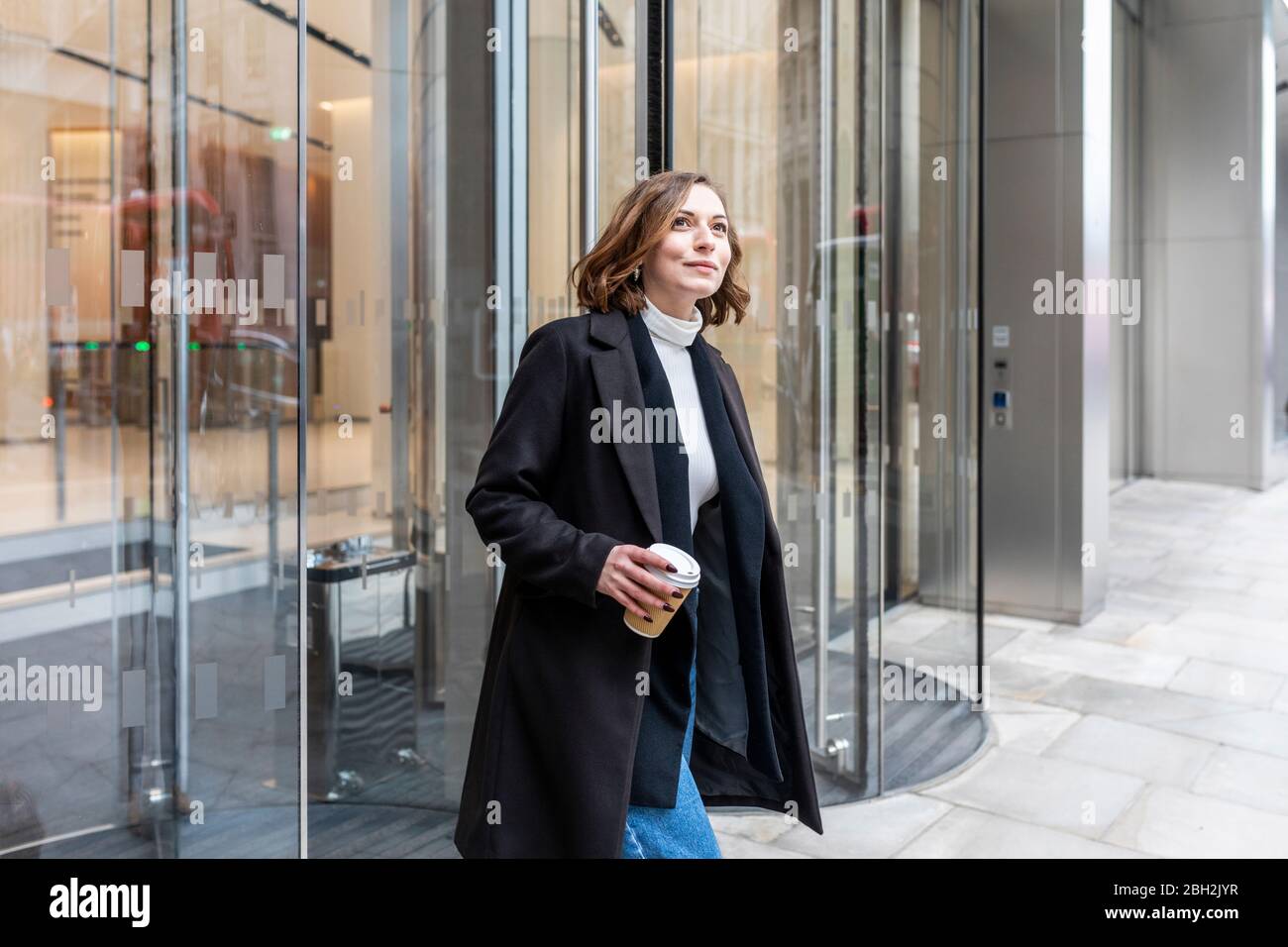 Woman in the city coming out from revolving door, London, UK Stock Photo