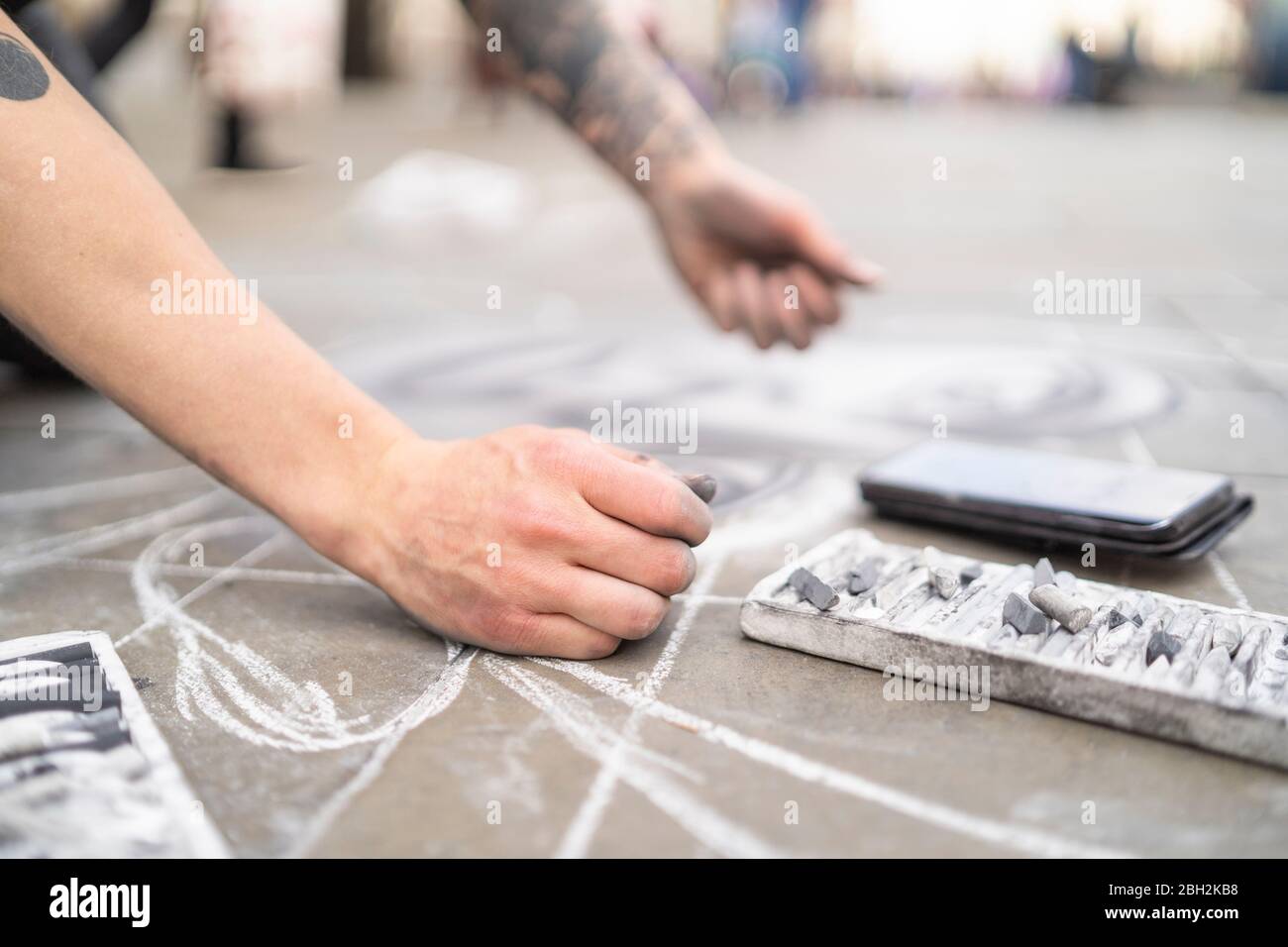 Street art, pavement artist drawing on pavement and using smartphone Stock Photo