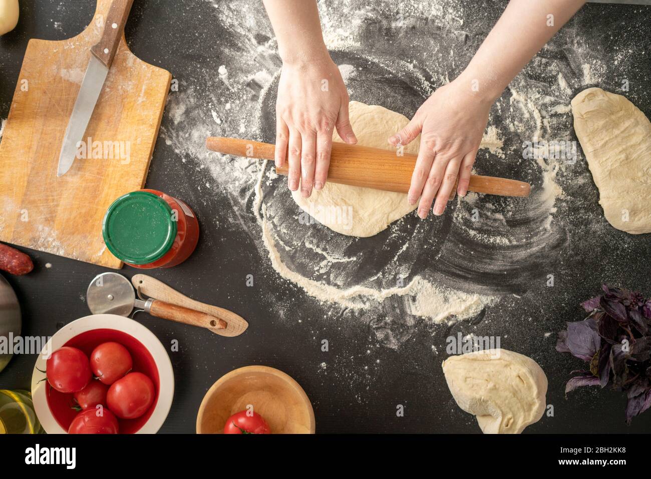 Woman's hands rolling out dough on worktop Stock Photo