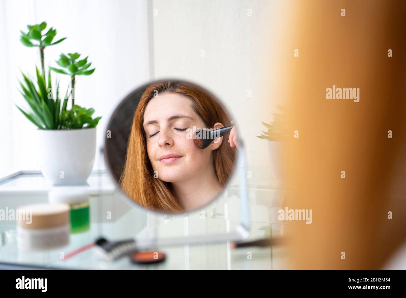 Young woman applying make up at home Stock Photo
