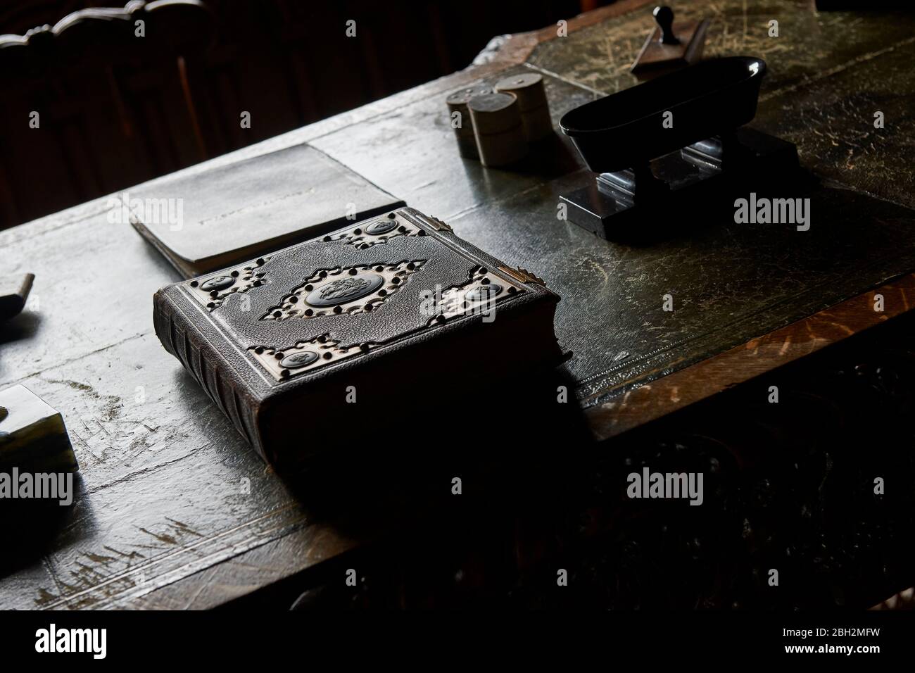 Antique unopened large bound book on an old oak desk table in natural light Stock Photo