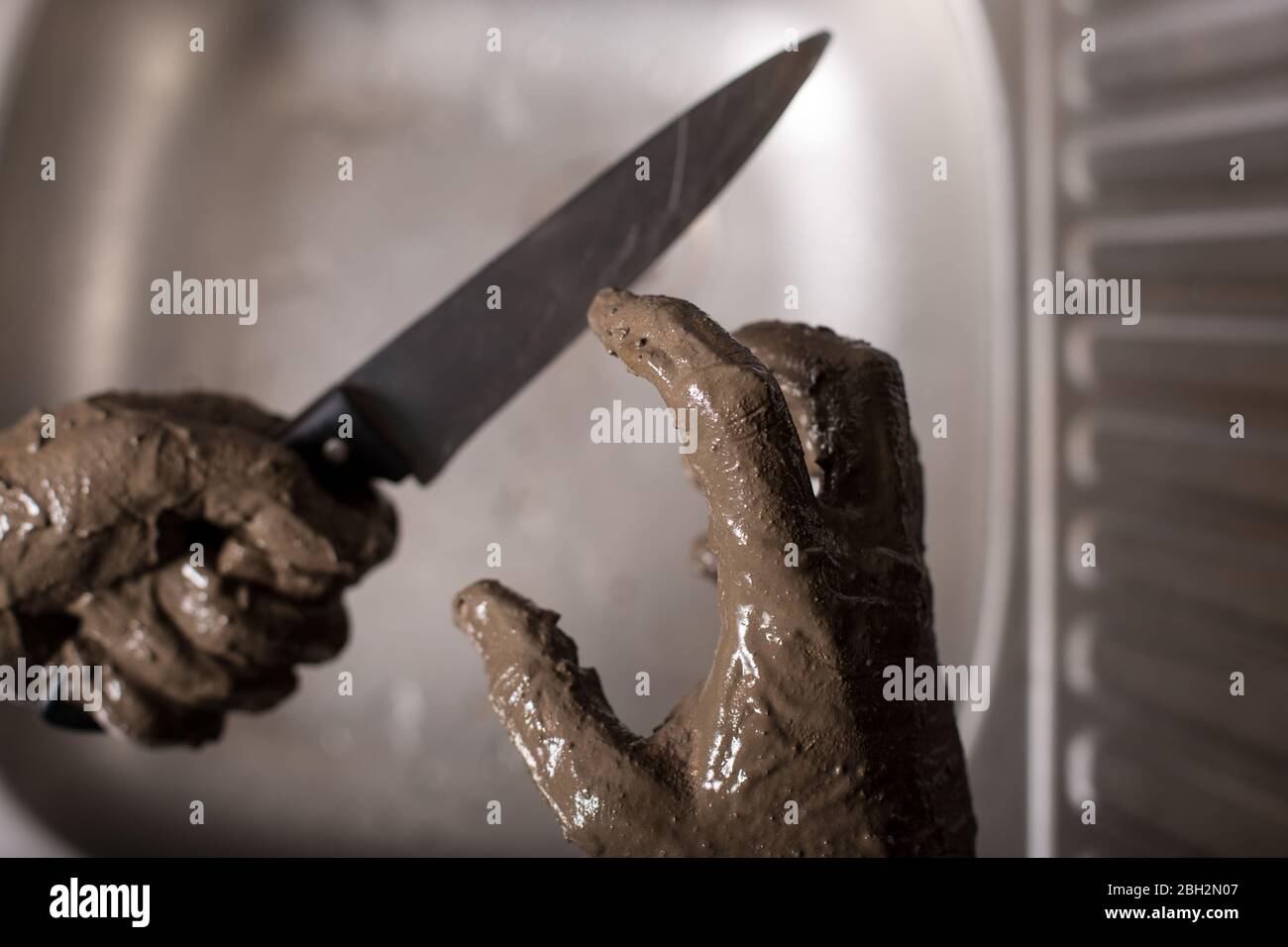 Dirty hands of killer holding a knife. Trying to wash away the traces of a crime Stock Photo