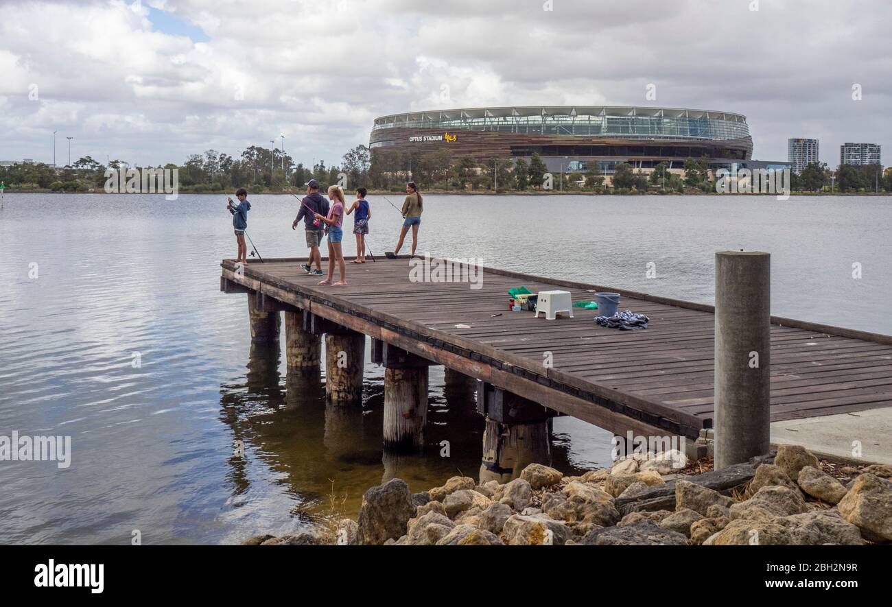 Father and children fishing off a wooden jetty on the Swan River and ...
