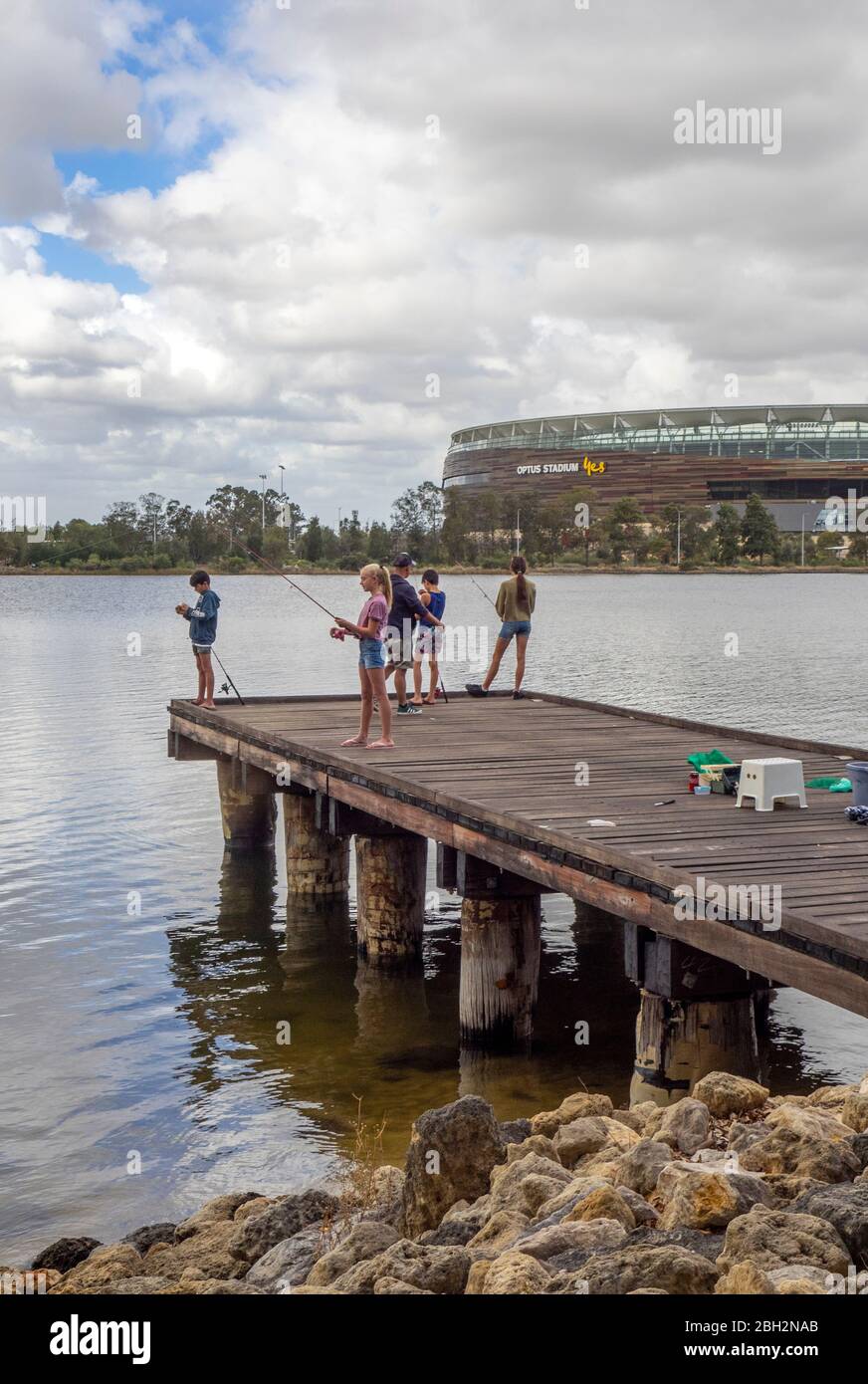 Father and children fishing off a wooden jetty on the Swan River and ...