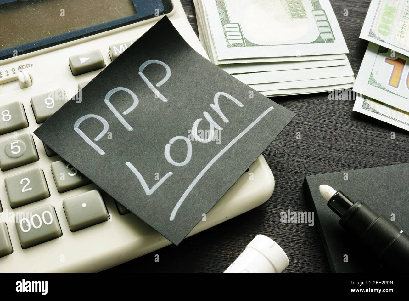 Memo sign PPP Loan Paycheck Protection Program on the black piece of paper. Stock Photo