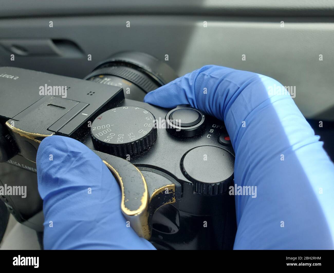 Gloved hands of a news photographer are visible holding a Leica Q digital camera during an outbreak of COVID-19 coronavirus in San Ramon, California, March 24, 2020. () Stock Photo