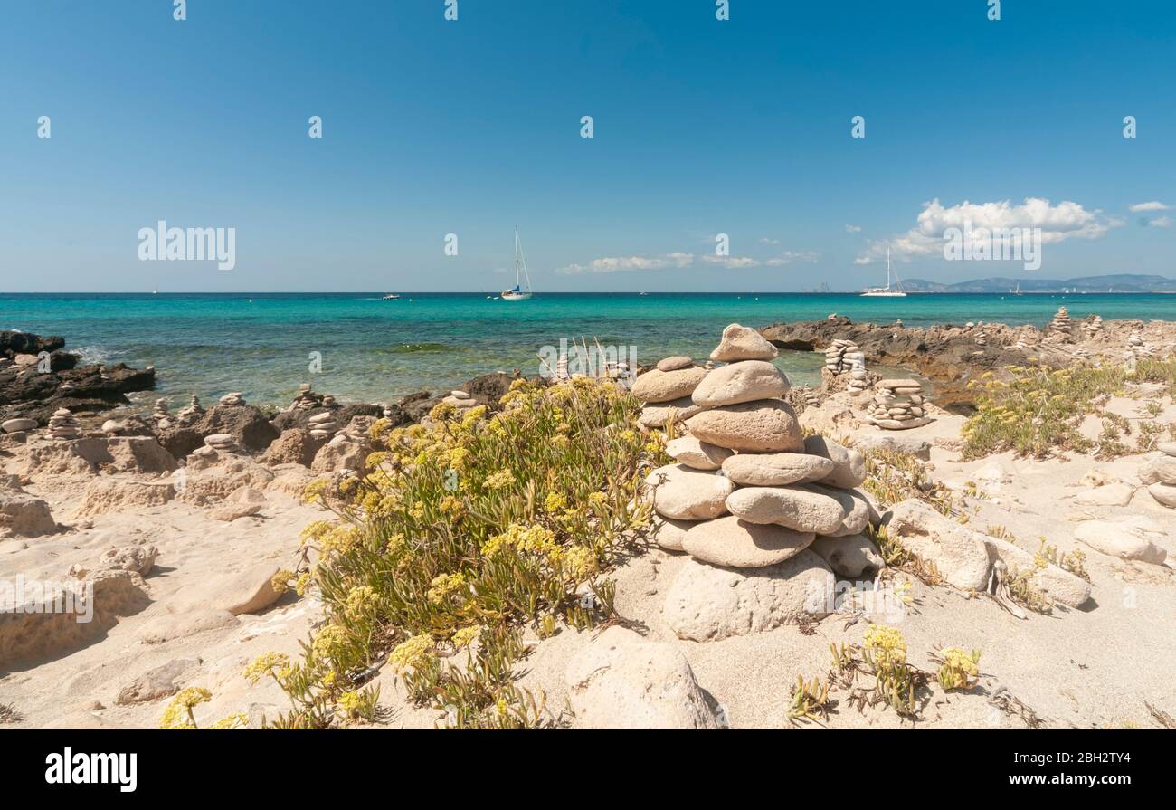 Panoramic view of a sandy and rocky beach. In the background the Mediterranean sea with sailing boats moored in the quiet bay of Formentera, Balearic Stock Photo