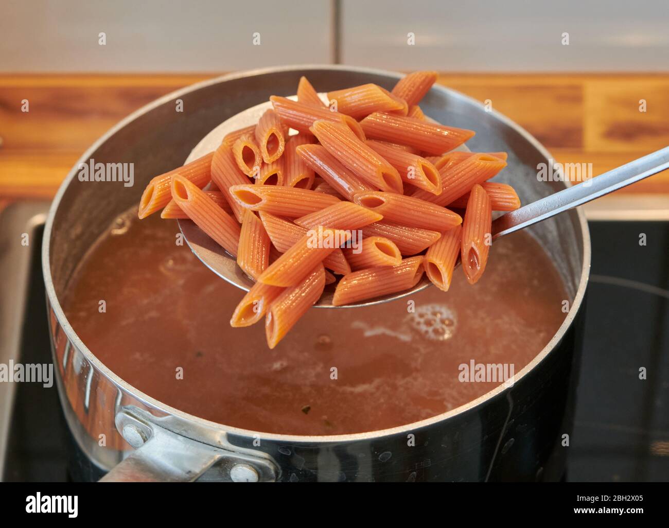 Italian pasta gluten-free and vegan, with lentil flour, while it is drained from the pot in the kitchen Stock Photo