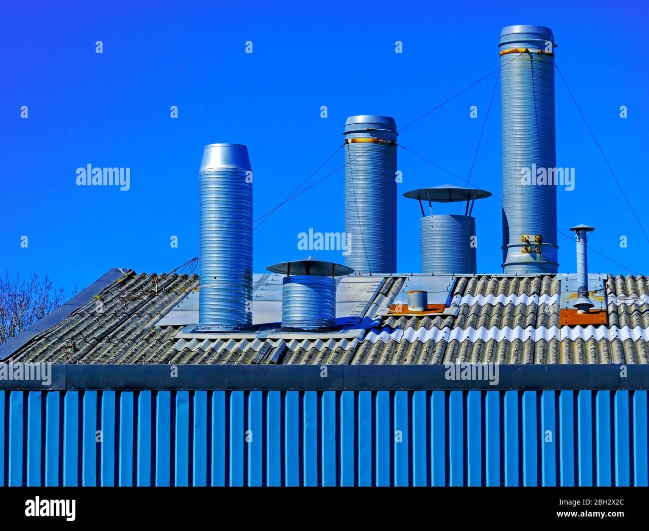 Set of 3 large ventilation ducts above factory roof against deep blue sky Stock Photo Alamy
