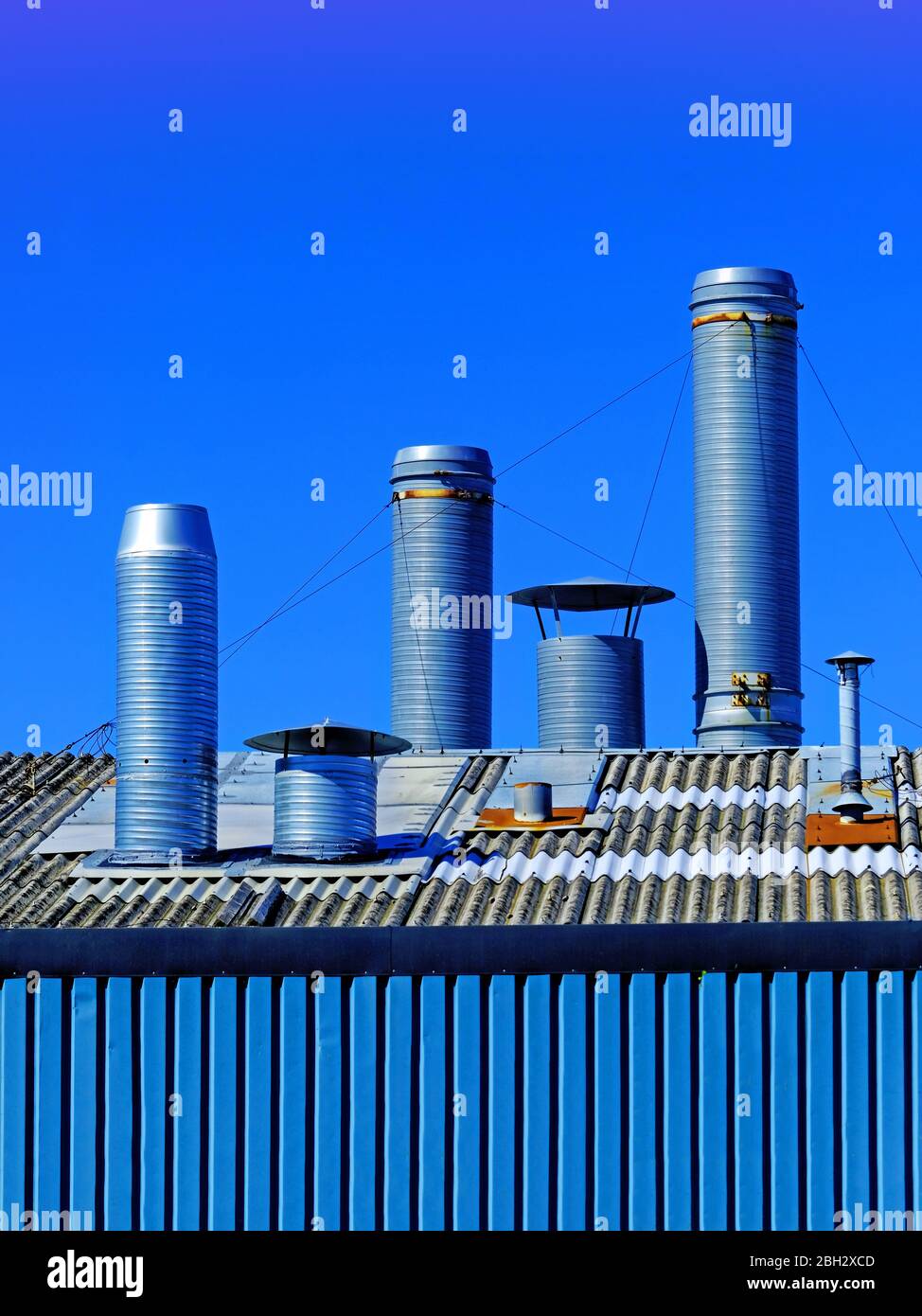 Set of 3 large ventilation ducts above factory roof against deep blue sky Stock Photo Alamy