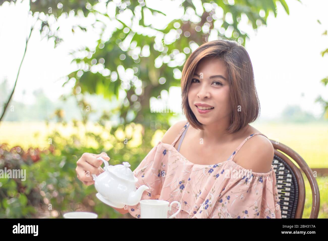 Kettles is made from ceramic tile in the hands of Asian women background blurry tree. Stock Photo
