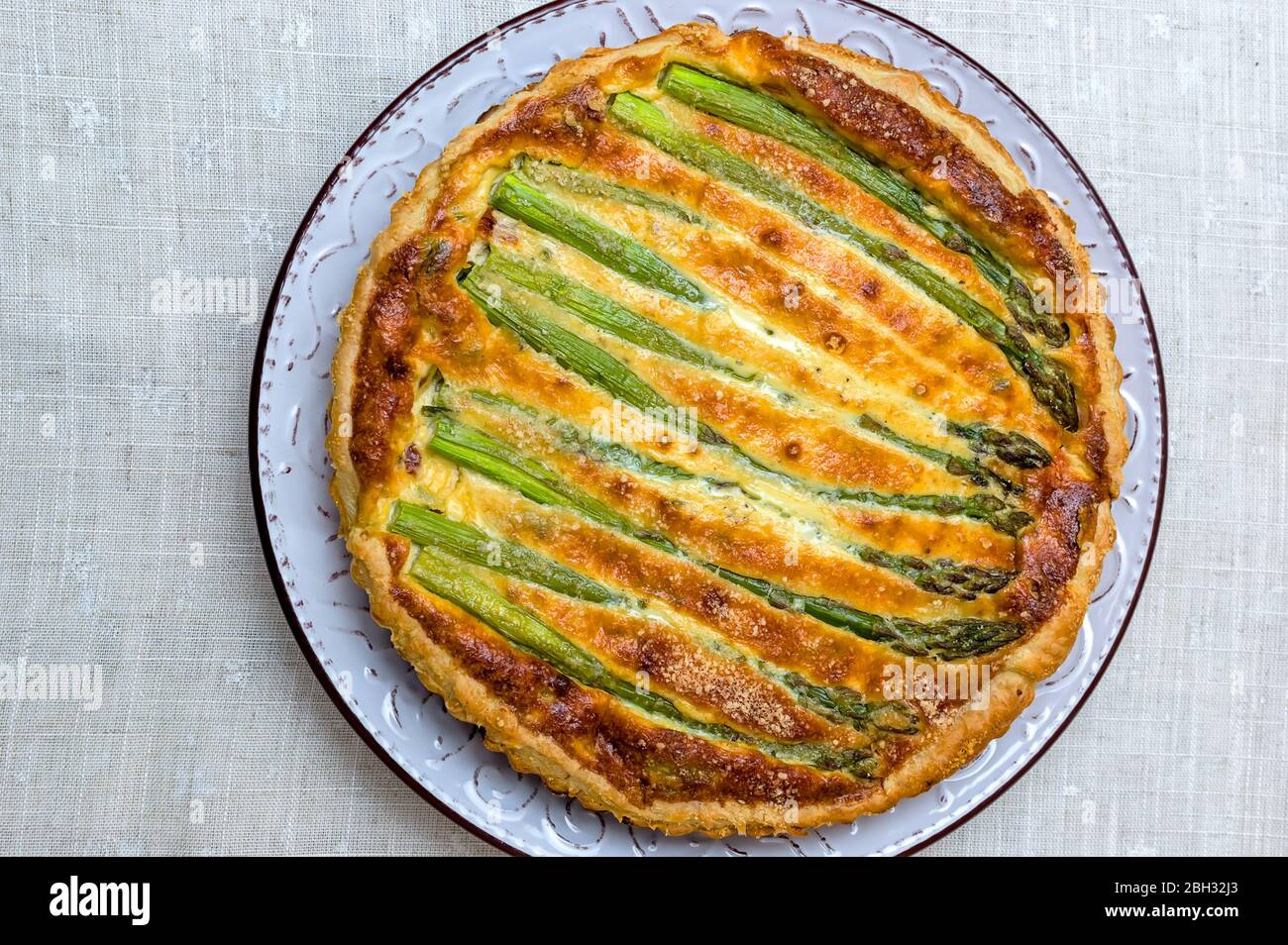 Tart with green asparagus and toasted cheese on the table Stock Photo