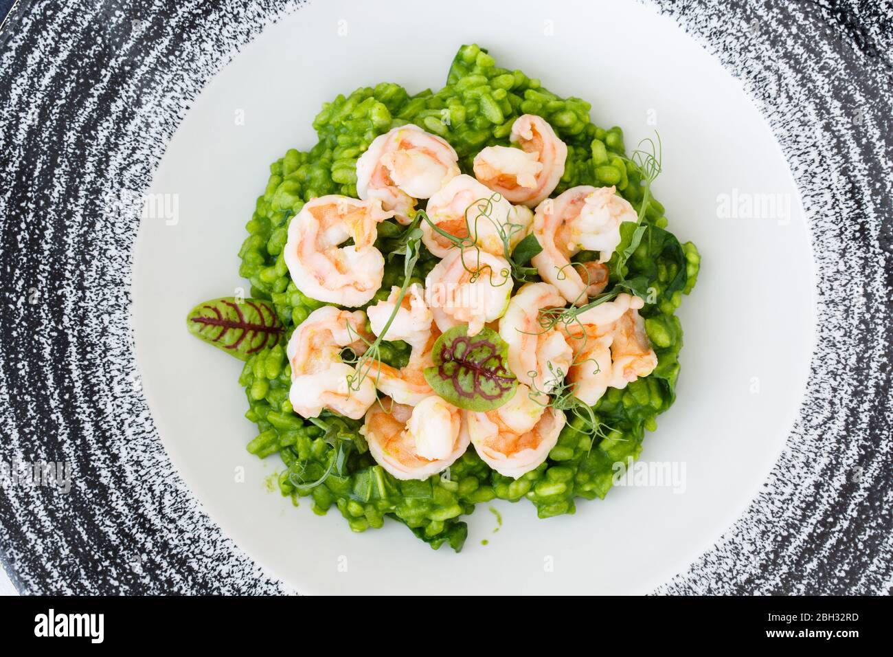 Risotto with basil and shrimp decorated with microgreens in a plate. Stock Photo