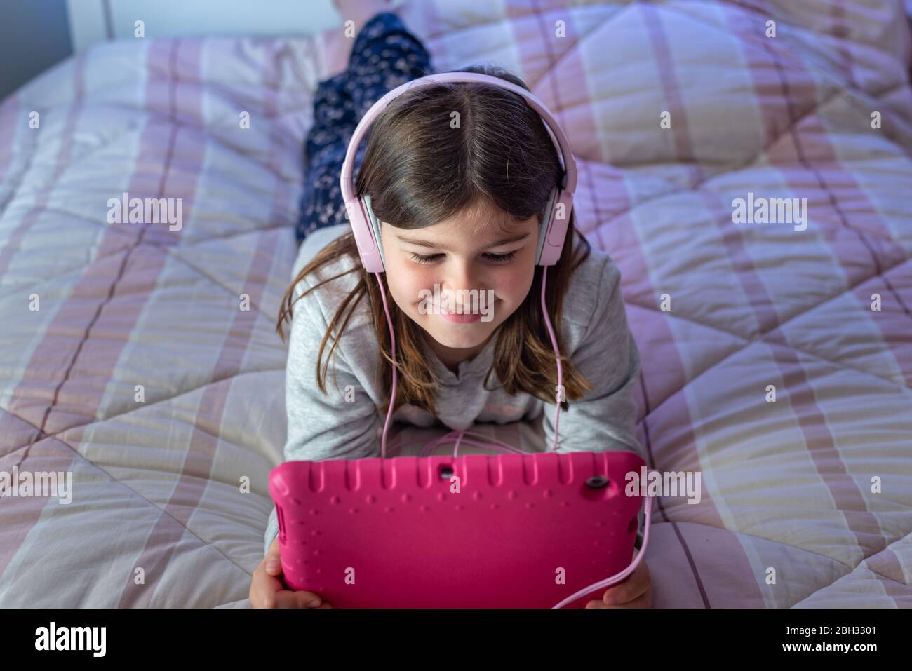 Cute little girl using tablet while lying in bed Stock Photo - Alamy