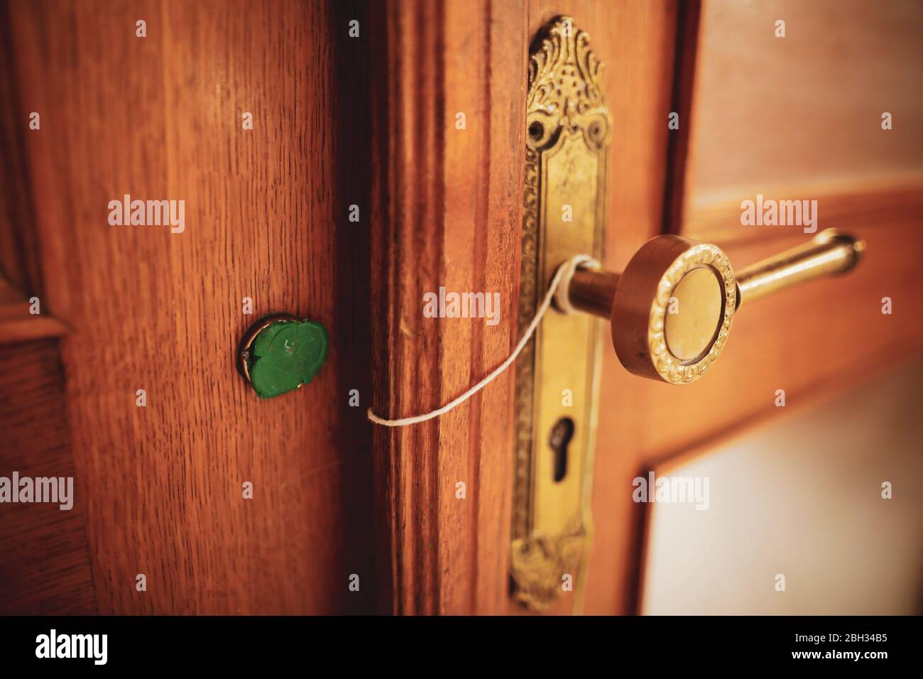 Shallow depth of field (selective focus) details with a broken wax seal on an old massive wooden door. Stock Photo
