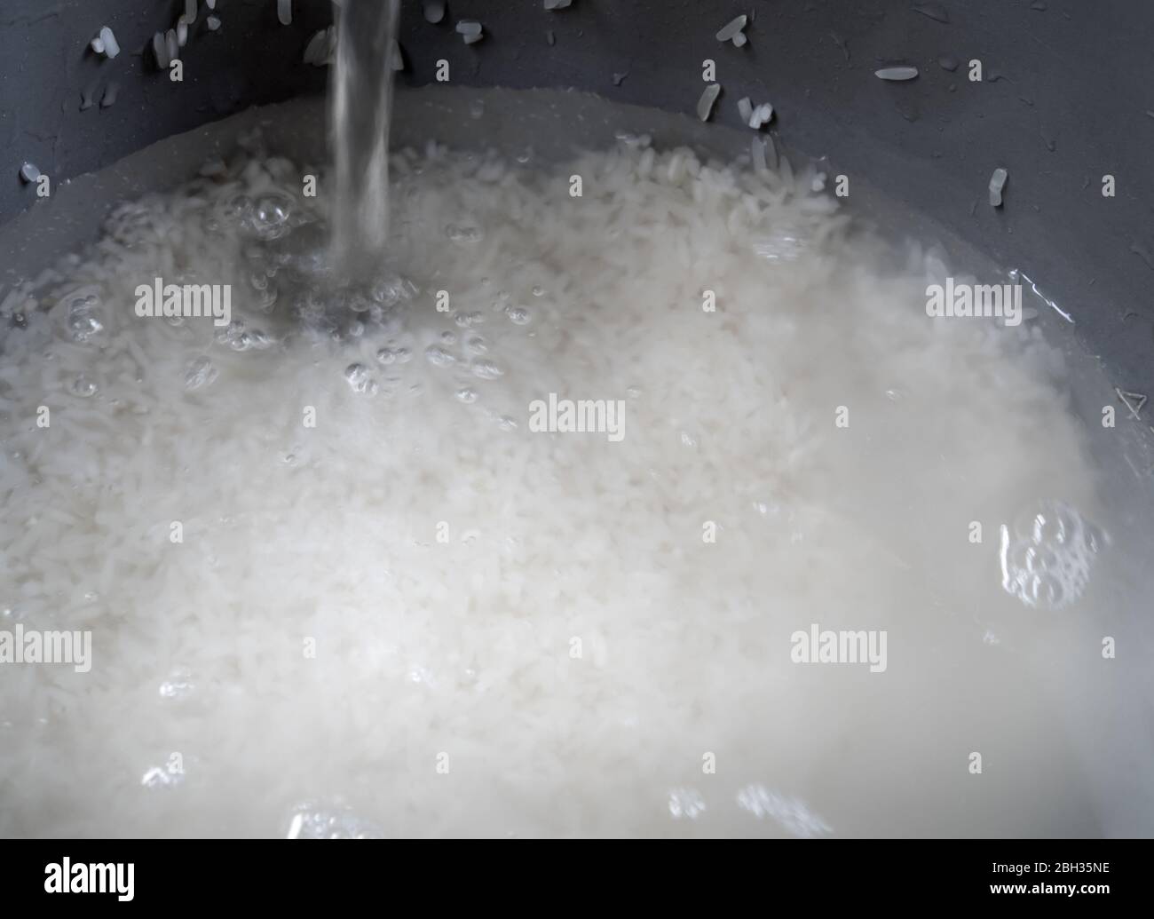 Rice prepared for cooking in an electric rice cooker Stock Photo - Alamy
