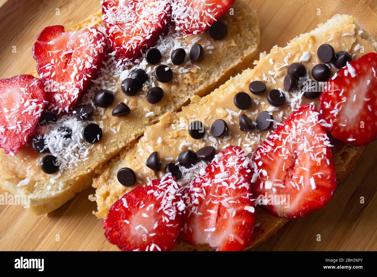 Peanut butter spread toasts with chocolate chips, strawberries, coconut flakes and homemade