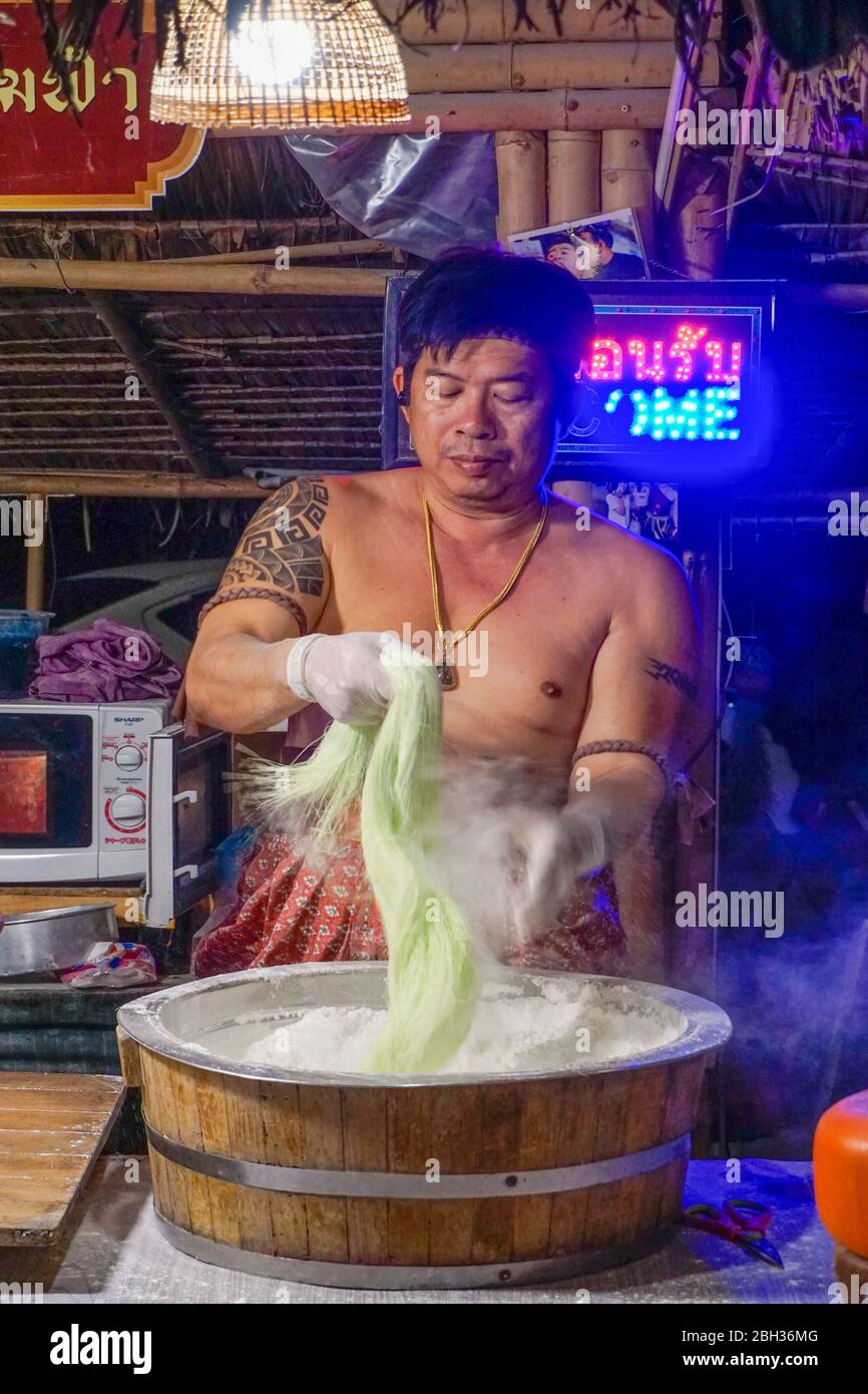 Food stall with man in traditional costume forming noodles at Kungsri night market in Ayutthaya, Thailand Stock Photo
