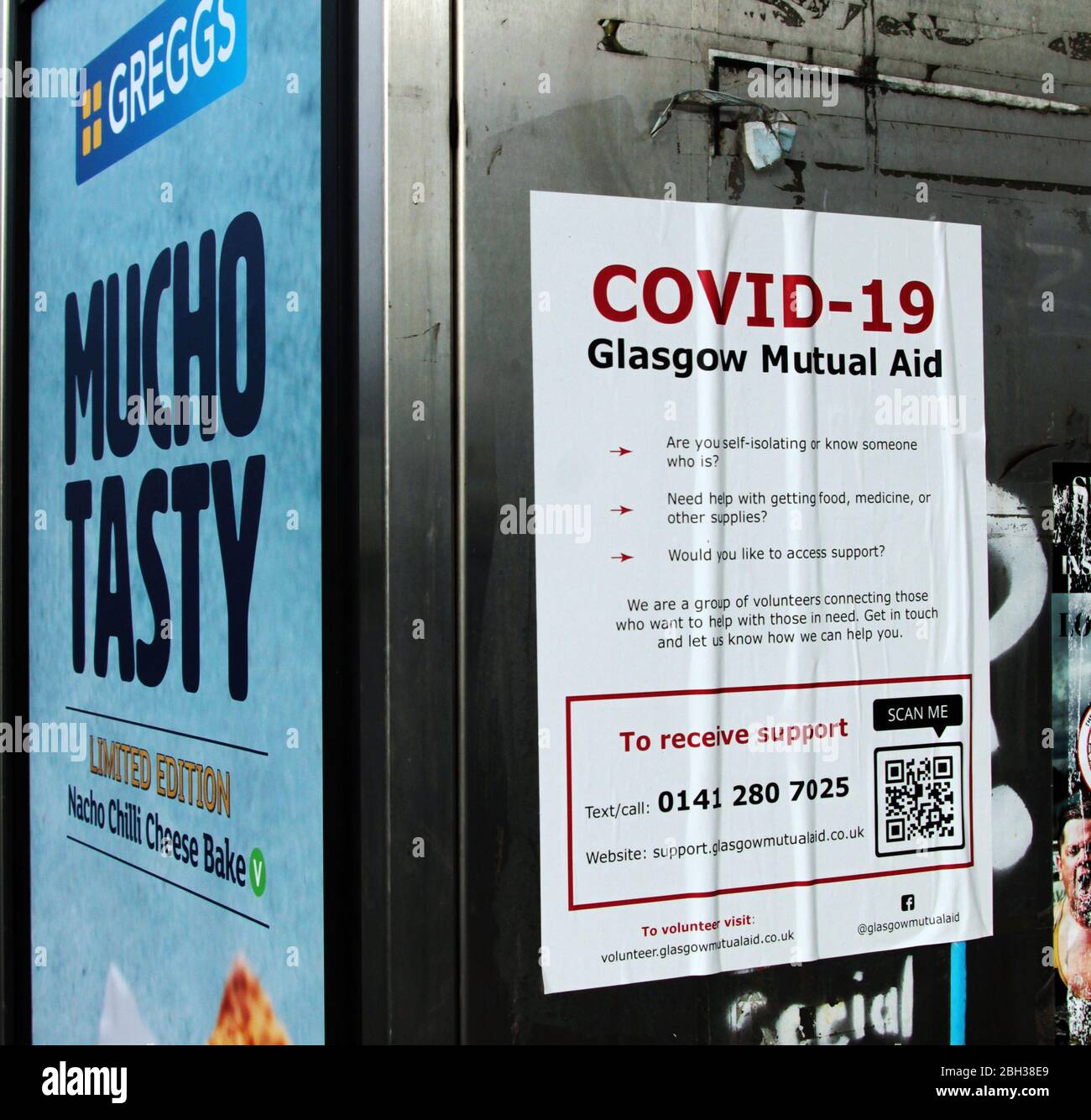 A Greggs bakery sign next to a help and advice poster giving information on where to get help during this Covid-19 and coronavirus pandemic that is raging though Britain. The whole country is in lockdown. Glasgow. April 2020. ALAN WYLIE/ALAMY© Stock Photo